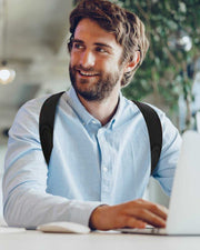 Copper Compression Posture Corrector, a man working at a laptop while wearing the posture corrector