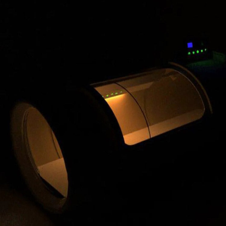 OxyRevo Quest36 chamber in a darkened room with amber interior lighting glowing through the circular door