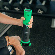 Rapid Release® P3i Vibration Massager held by its green grip at a dumbbell rack