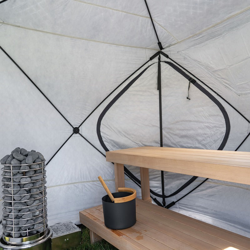 Tent interior with a bench and backrest along one wall and the heater's stone column at the end