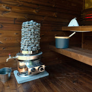 Tank fitted to the heater in a cedar sauna, bucket alongside