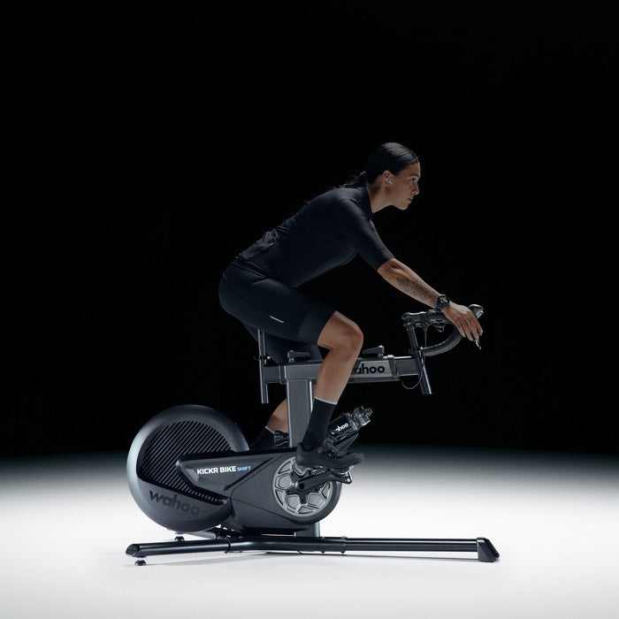 Wahoo KICKR BIKE SHIFT, rider in dark kit pedalling against a black backdrop