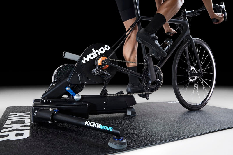 Wahoo KICKR MAT, mat under a trainer with rider's legs and bike, dark room